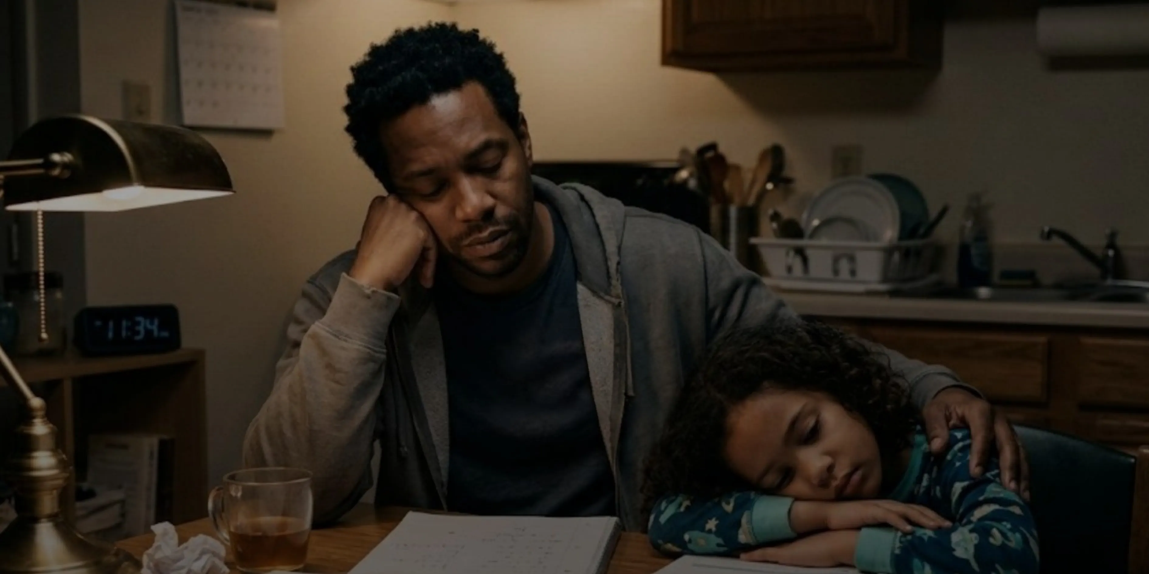 A father stays up late at the kitchen table helping his daughter with homework.